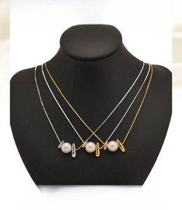 Detailed close-up of gold and silver snake chains featuring elegant pearl pendants on a bust