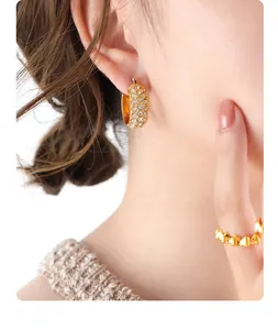 Close-up of gold-plated C-shaped hoop earrings with multi-row pavé crystals on model