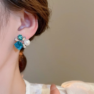 Close-up of vintage floral earrings with blue crystals and white pearls for women