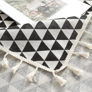 Macro detail of cotton linen tablecloth with black geometric pattern and beige tassels
