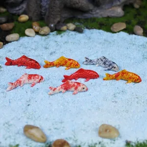 Miniature koi fish figurines on blue sand for garden micro landscape decor