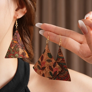 Close-up of bohemian triangle cork earrings with colorful floral prints on a model