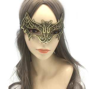 Detail view of a gold and black bat-shaped lace mask worn on a white head model