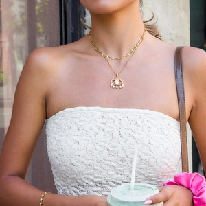 Detail of layered gold evil eye necklace with pearls and matching link bracelet set