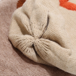 Close-up of beige, brown, and orange knit texture with precision stitching on top