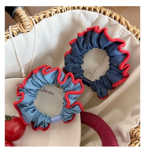 Close-up of denim scrunchies with vibrant red ruffled edges and plastic buckle detail