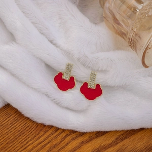 Detail of red enamel earrings with gold plating and rhinestones on soft white fur