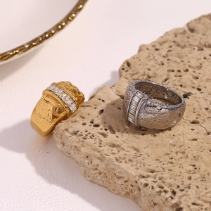 Close-up of gold and silver thick bands with square zircon row on natural stone with water drops