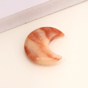 Polished orange and cream crescent moon natural agate crystal stone ornament on sand