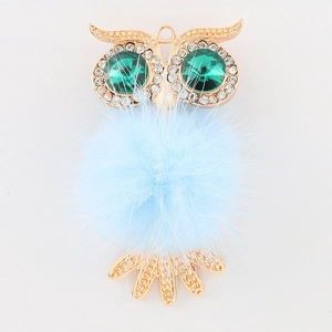 Détail d'accessoire chouette avec pompon bleu clair et yeux en cristal vert sur alliage