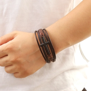 Close-up of a multi-layer brown leather bracelet with a matte black alloy cross