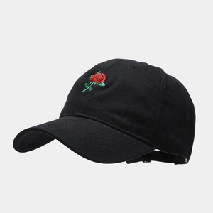 Dettaglio del ricamo a rosa rossa su un berretto da baseball in cotone nero con foglie
