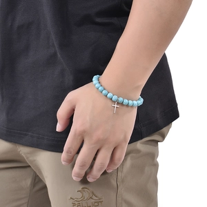 Close-up of handmade pink zebra stone and blue turquoise beaded cross bracelet on wrist