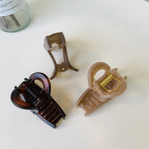 Detail view of medium butterfly hair claws in amber, brown, and beige with metal springs