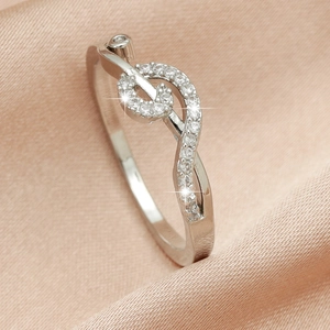 Macro shot of silver treble clef ring with pavé zircons on elegant silk background