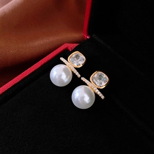 Macro shot of a square crystal and pearl stud earring on a red jewelry box velvet