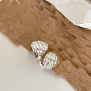 Macro shot of S925 sterling silver hoop earrings with wave texture and shell-like design