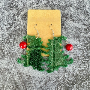 Detailed view of Christmas tree acrylic earrings with green sequins and red bead accents