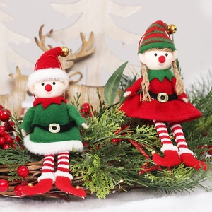 Pair of Christmas elf doll hanging ornaments on festive pine branches with berries