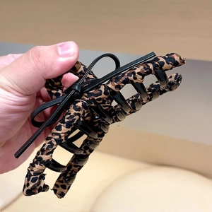 Détail macro de la grande pince à cheveux léopard avec un nœud en cuir noir chic