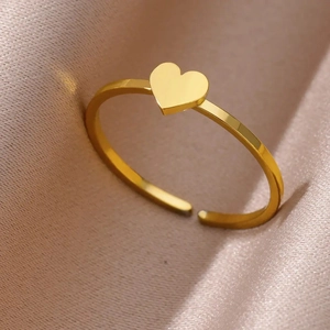Detailed view of an adjustable gold-plated heart ring on elegant pink silk fabric