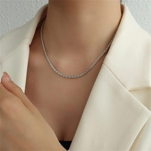 Détail d'un collier en acier inoxydable argenté texturé porté par un mannequin en blazer