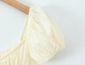 Detailansicht der cremefarbenen Puffärmel und elastischen Schulterpartie mit Knitteroptik