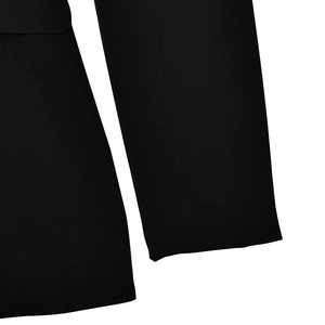 Detailed close-up of the woven black fabric texture and sleeve stitching of the dress