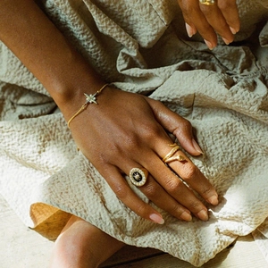 Detail of vintage gold jewelry set featuring starburst ring and serpent band on model
