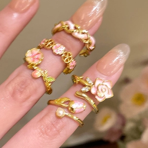 Detail of 18k gold plated adjustable rings with pink enamel flowers and pearls