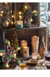 Close-up of birch wood candle holder with red berries and warm LED lights for Christmas decor