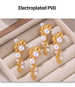 Macro view of PVD plated gold earrings with white pearls and sparkling zircons in a box