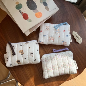 Detailed top view of quilted cotton coin pouches with cute animal embroidery on wood