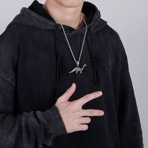 Silver dinosaur pendant necklace on twisted rope chain worn over black hoodie