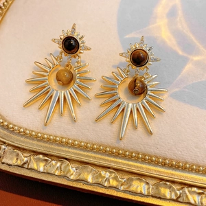 Detail of gold starburst earrings with brown tiger eye stone and small zircon accents