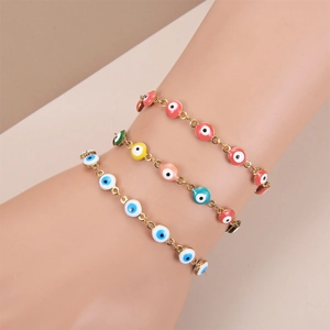 Close-up of three gold-plated evil eye bracelets with colorful enamel beads on a wrist