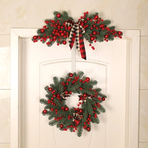 Christmas wreath and swag set with red berries and plaid bows on a white wooden door