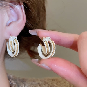 Detail of 18k gold plated double-layer C-shape hoop earrings with white enamel finish