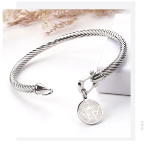 Detailed macro of silver twisted stainless steel rope bracelet with St. Benedict medal