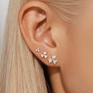 Detailed view of three-piece heart-shaped gold stud earrings with white zirconia stones