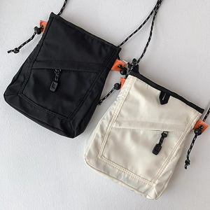 Detail view of nylon crossbody phone bags in black and beige with orange accents