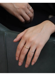 Close-up of gold geometric rhombus ring and silver minimalist band on model fingers