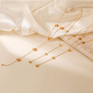 Elegant gold chain necklace featuring delicate heart and star fringe charms on silk fabric