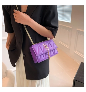 Detail shot of a purple quilted crossbody bag with gold chain strap on a model