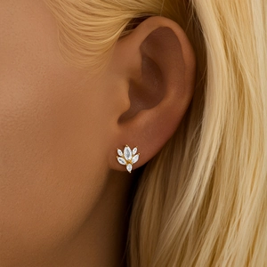 Detail view of gold flower cartilage earrings with green zircon on a female model's ear