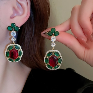 Detail of vintage French style gold earrings with green and red gemstones on model