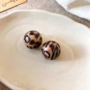 Detailed view of round leopard print resin earrings on a white decorative ceramic tray
