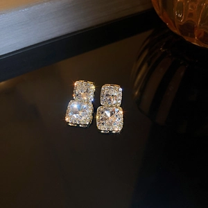 Macro shot of elegant golden square stud earrings featuring brilliant sparkling cubic zirconia