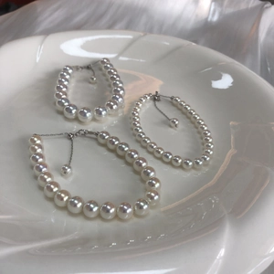 Detailed view of s925 silver pearl bracelets in three sizes on a white porcelain plate