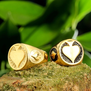 Gold spade and heart stainless steel rings on a rustic stone background with green leaves